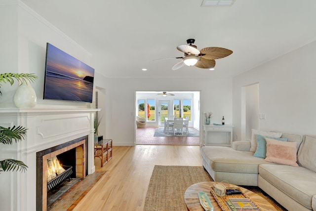 living room featuring a fireplace, french doors, light wood-type flooring, and crown molding