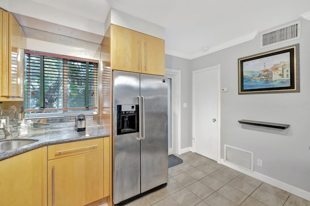 kitchen with crown molding, sink, stainless steel fridge, dark stone countertops, and light tile patterned floors