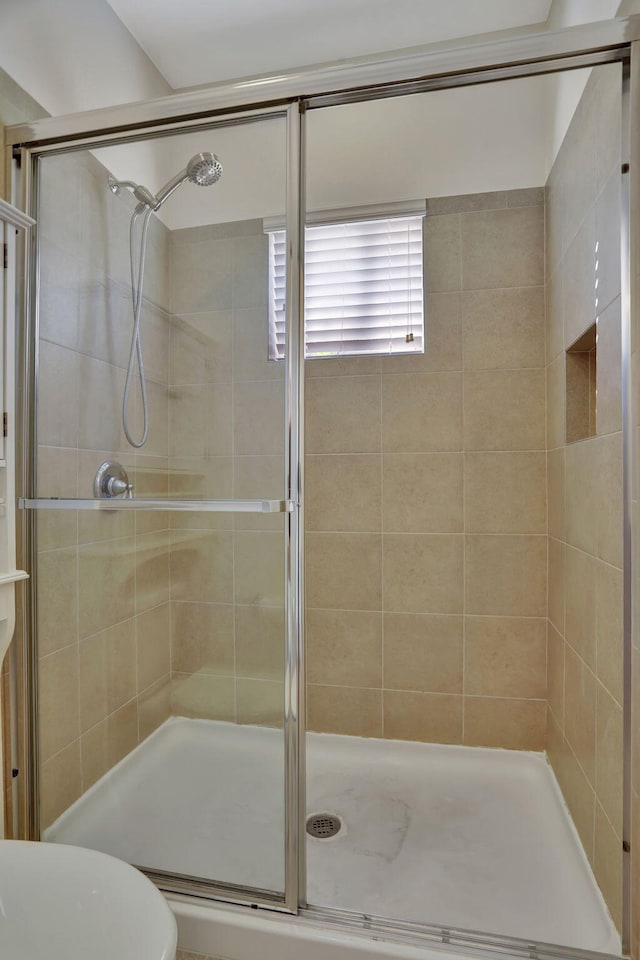 bathroom with a shower with shower door and toilet