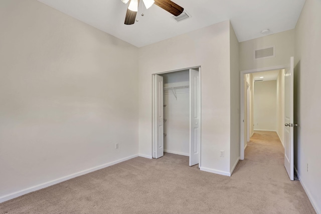 unfurnished bedroom with ceiling fan, light carpet, and a closet