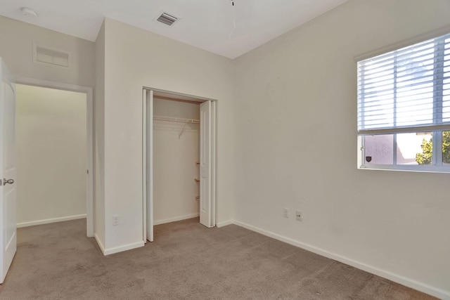 unfurnished bedroom with a closet, light carpet, and multiple windows