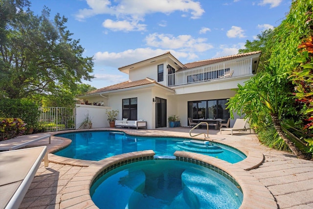 back of house featuring a balcony, a patio, and a pool with hot tub