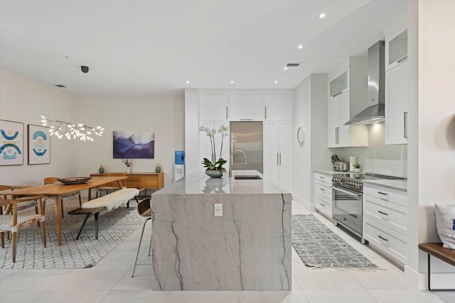 kitchen featuring appliances with stainless steel finishes, sink, wall chimney range hood, light tile patterned floors, and hanging light fixtures