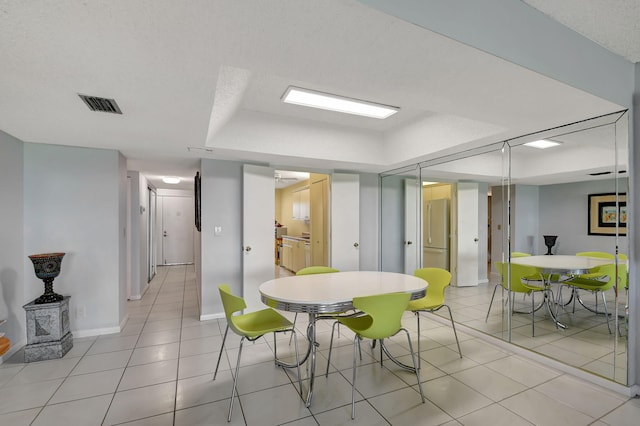 tiled dining space with a textured ceiling