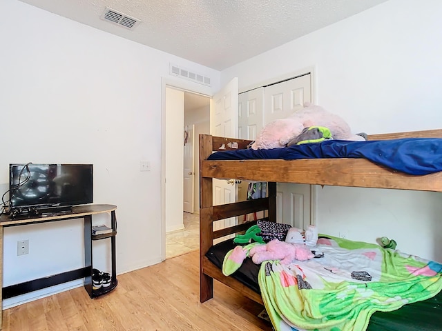 bedroom featuring a textured ceiling, light hardwood / wood-style flooring, and a closet