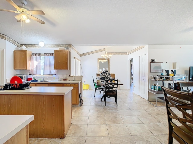 kitchen featuring pendant lighting, ceiling fan with notable chandelier, sink, light tile patterned floors, and a textured ceiling