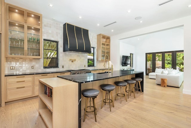 kitchen with tasteful backsplash, custom range hood, sink, light brown cabinets, and light hardwood / wood-style flooring