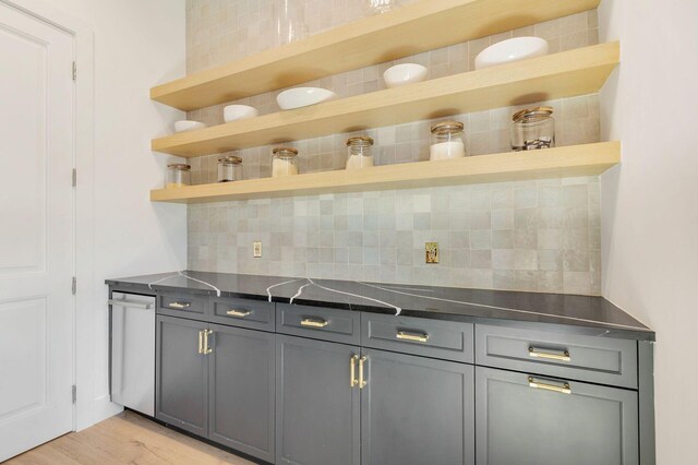 bar featuring decorative backsplash, gray cabinets, and light hardwood / wood-style flooring