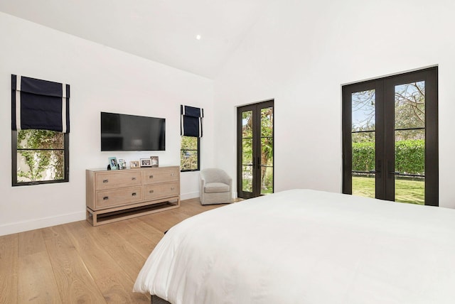 bedroom with access to exterior, french doors, light hardwood / wood-style flooring, and multiple windows