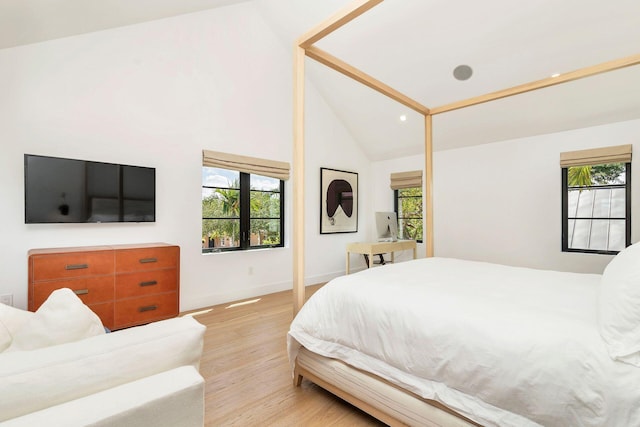 bedroom featuring light hardwood / wood-style flooring, high vaulted ceiling, and multiple windows