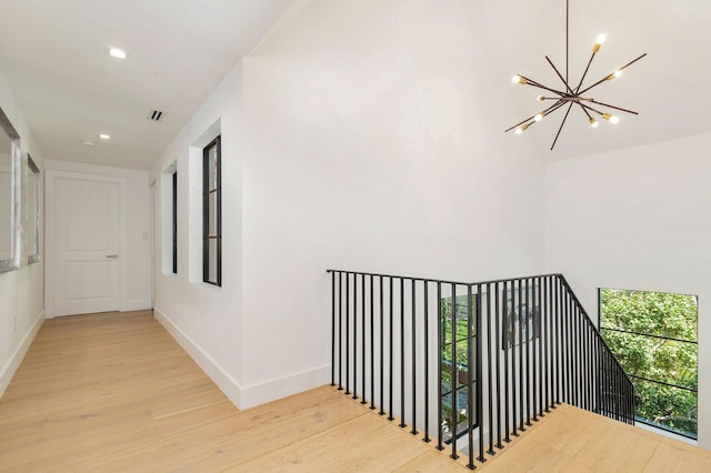 hallway featuring an inviting chandelier and light hardwood / wood-style flooring