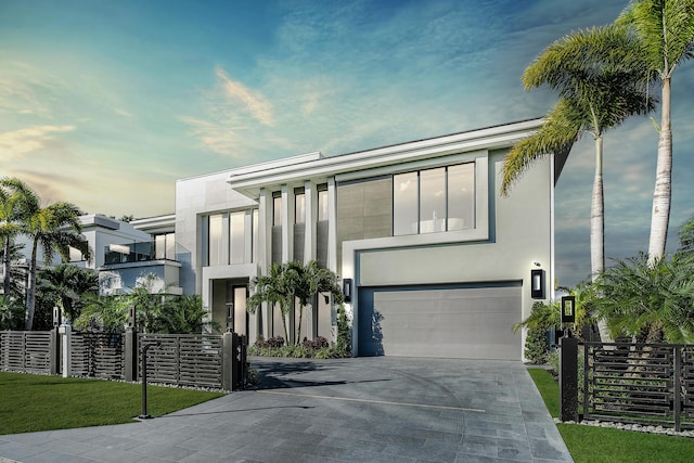 modern home with driveway, fence, a garage, and stucco siding
