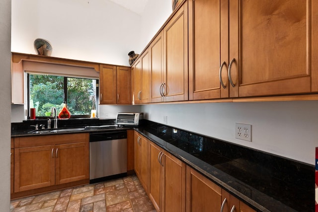 kitchen with stainless steel dishwasher, dark stone counters, and sink