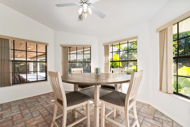 dining area featuring ceiling fan, lofted ceiling, and a textured ceiling