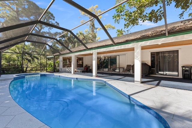 view of pool with glass enclosure and a patio