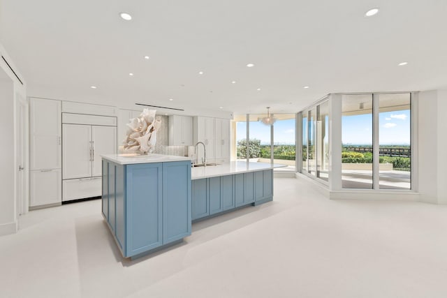 kitchen with paneled fridge, blue cabinets, a large island, and sink