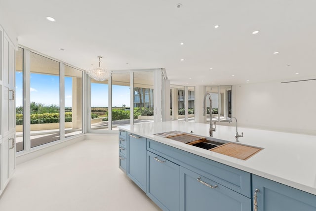 kitchen with blue cabinetry, sink, pendant lighting, and an inviting chandelier