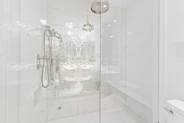 bathroom featuring a tile shower and toilet