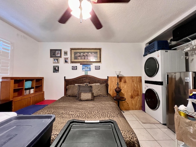 tiled bedroom with stacked washer / dryer, ceiling fan, and a textured ceiling