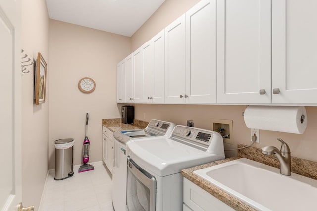 clothes washing area featuring washer and clothes dryer, sink, and cabinets