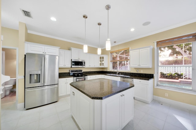 kitchen featuring a center island, crown molding, decorative light fixtures, white cabinetry, and stainless steel appliances