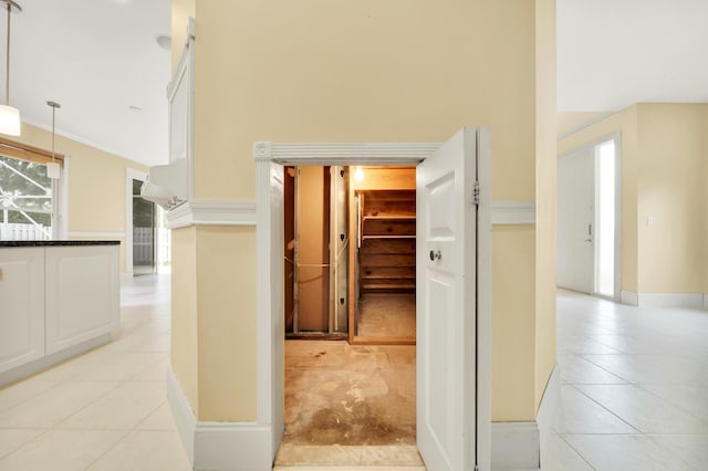 hallway featuring ornamental molding and light tile patterned floors