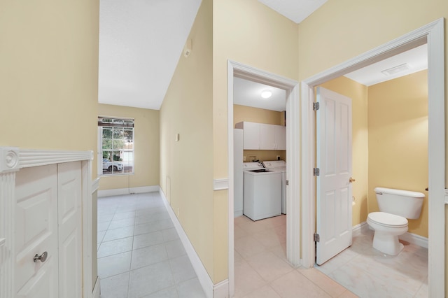 hallway with separate washer and dryer and light tile patterned floors