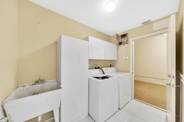 laundry room with cabinets, light carpet, a textured ceiling, sink, and washing machine and dryer