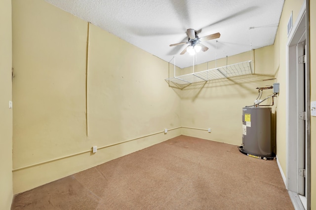 basement featuring a textured ceiling, ceiling fan, electric water heater, and carpet floors