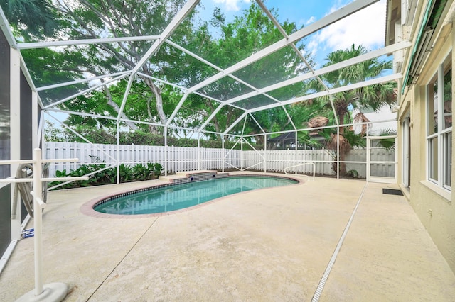 view of swimming pool featuring glass enclosure and a patio