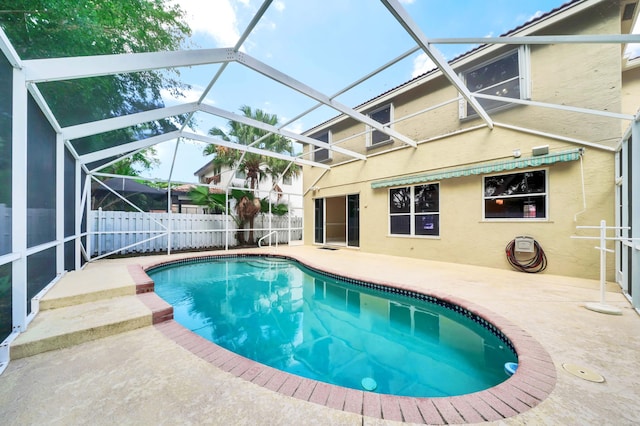 view of pool with glass enclosure and a patio