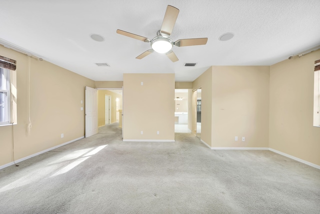 unfurnished room featuring ceiling fan, light colored carpet, and a textured ceiling