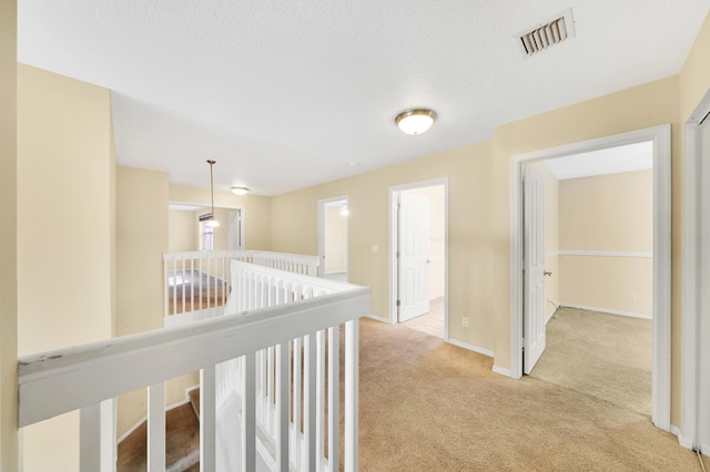 hall featuring light carpet and a textured ceiling