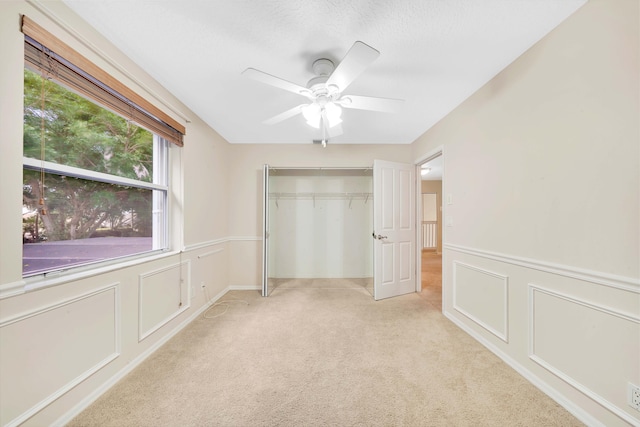 unfurnished bedroom featuring a closet, light colored carpet, and ceiling fan