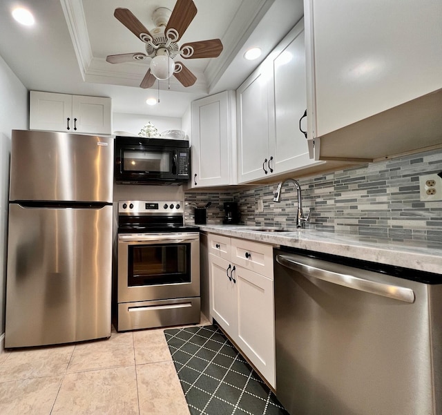 kitchen with white cabinetry, appliances with stainless steel finishes, decorative backsplash, and a tray ceiling