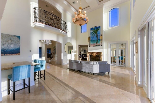 interior space with french doors, a healthy amount of sunlight, a notable chandelier, crown molding, and a towering ceiling