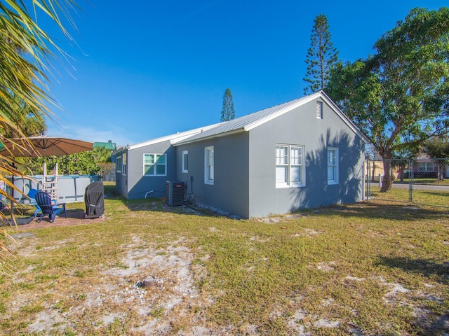 rear view of property with a lawn and cooling unit