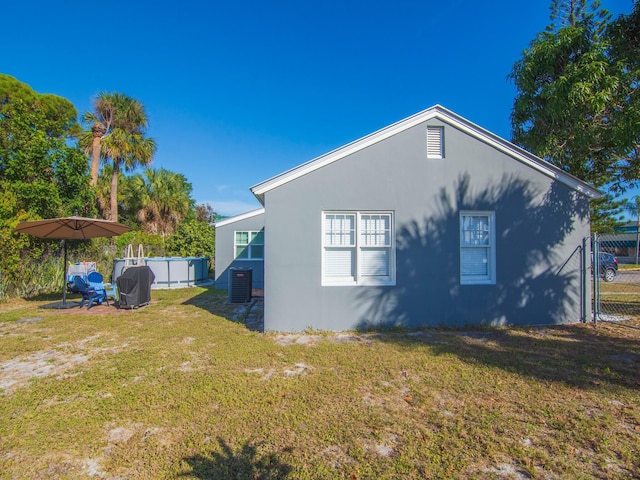 view of side of property featuring a yard, cooling unit, and a pool