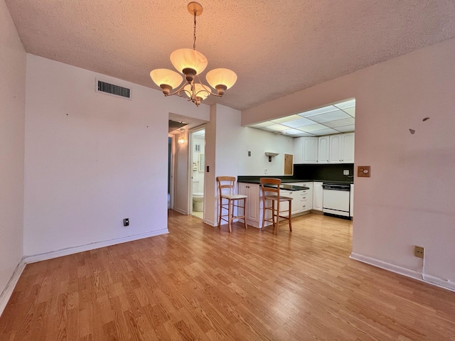 kitchen featuring dishwasher, decorative light fixtures, a notable chandelier, white cabinetry, and a breakfast bar area