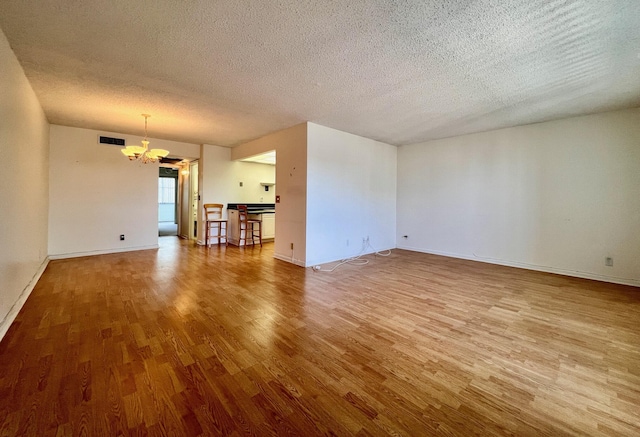 spare room with hardwood / wood-style floors, a textured ceiling, and a notable chandelier