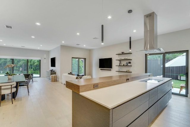 kitchen featuring electric stovetop, island exhaust hood, a spacious island, decorative light fixtures, and light wood-type flooring