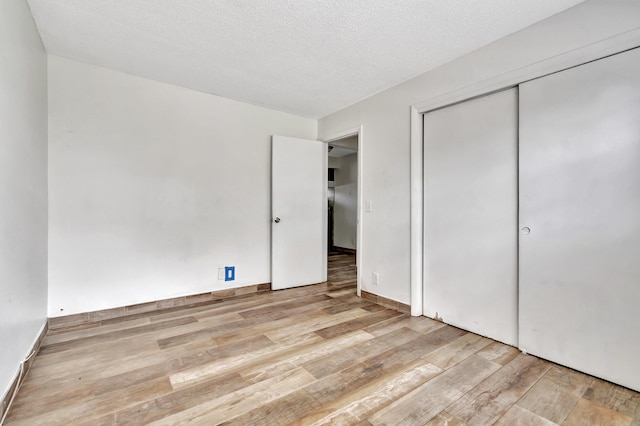 unfurnished bedroom featuring a textured ceiling, light hardwood / wood-style floors, and a closet