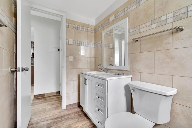 bathroom with hardwood / wood-style floors, vanity, toilet, and tile walls