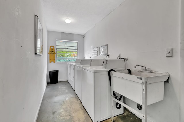 clothes washing area featuring washer and clothes dryer, sink, and a textured ceiling