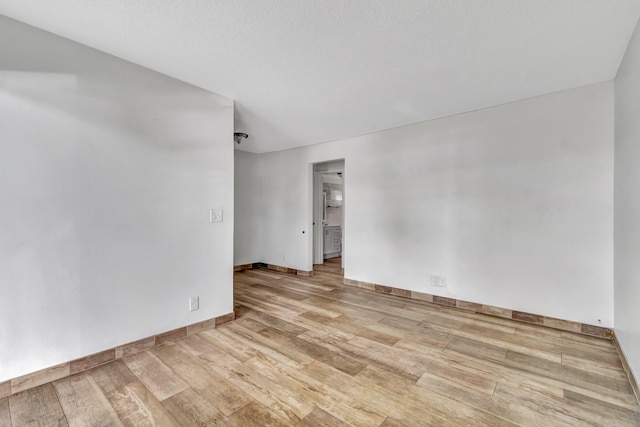 empty room with light hardwood / wood-style flooring and a textured ceiling