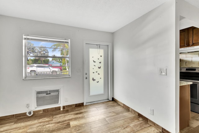 entrance foyer featuring light wood-type flooring, a textured ceiling, and a wall unit AC