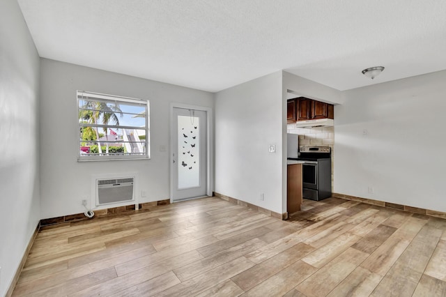 interior space featuring a wall mounted air conditioner, decorative backsplash, light wood-type flooring, and electric stove