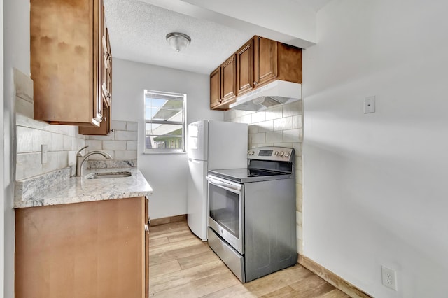 kitchen featuring sink, tasteful backsplash, light hardwood / wood-style floors, a textured ceiling, and electric stove