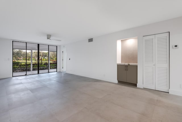 empty room with ceiling fan and expansive windows