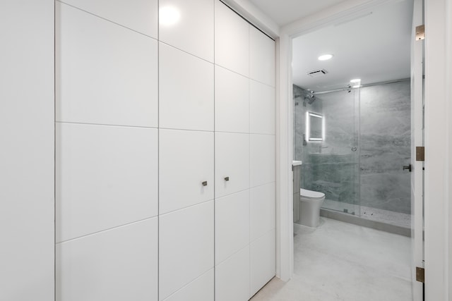 bathroom featuring toilet, tile walls, and a shower with shower door